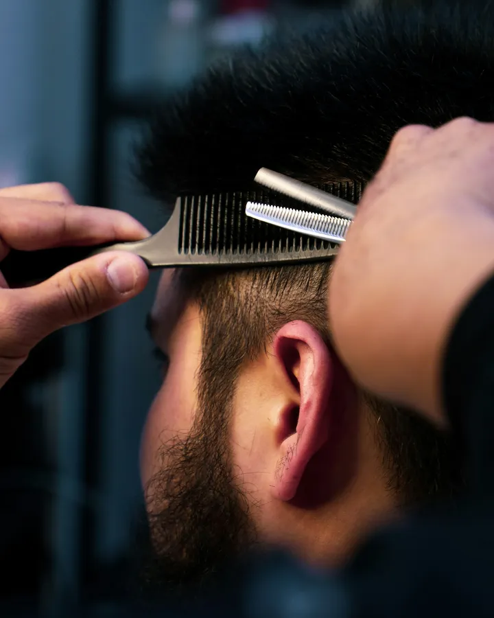 Corte clásico de caballero — peine de barbero sobre cabello, close-up editorial