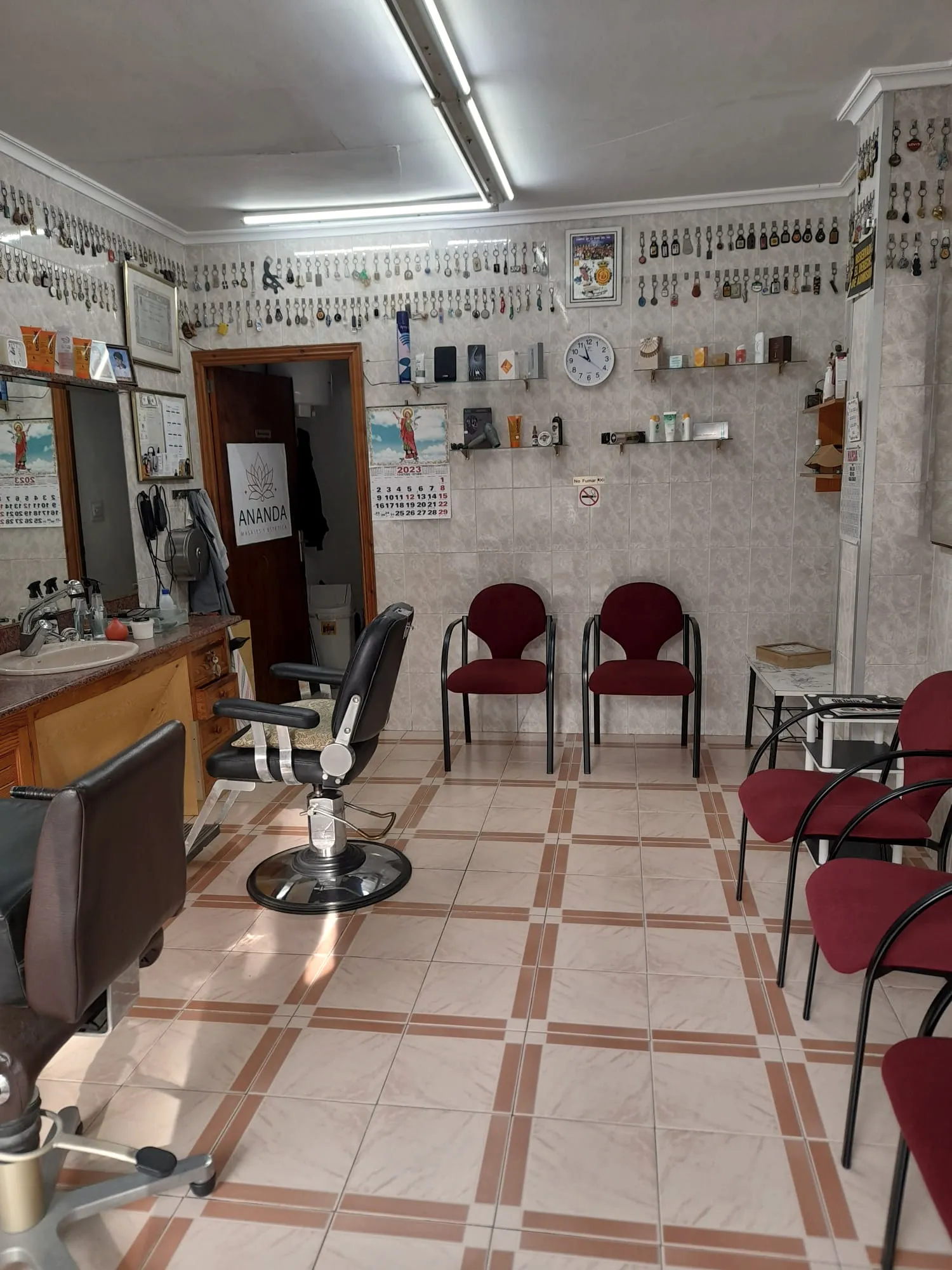 Interior de Peluquería Juan: muro de llaves de clientes, sillón de barbero y luz cálida del Vivero