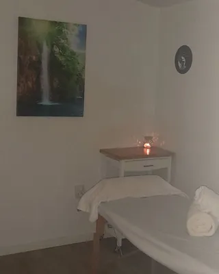 Cabina de quiromasaje en Peluquería Juan — camilla, velas y cuadro de cascada en ambiente cálido